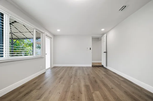 a view of an empty room with wooden floor and a window