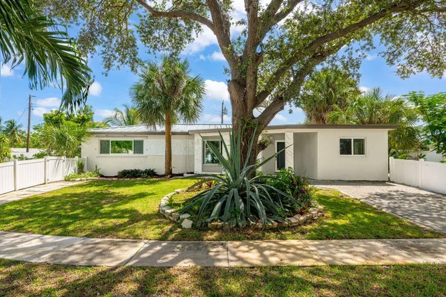 a view of a house with a tree in the yard next to a house