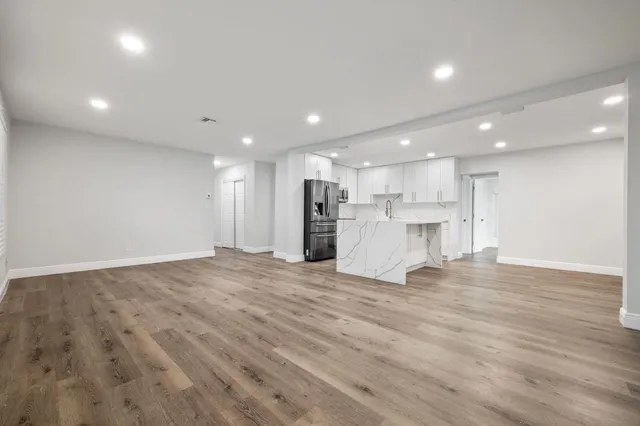 a view of an empty room with kitchen and a window