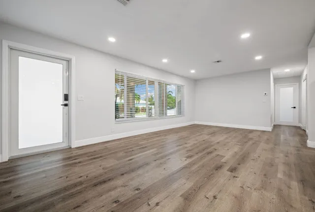 an empty room with wooden floor and windows