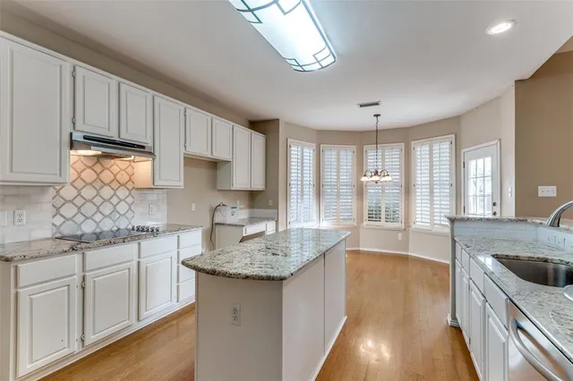 a kitchen with granite countertop a sink a counter space appliances and cabinets