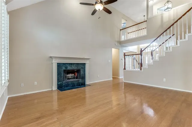 a view of an empty room with wooden floor fireplace and a window