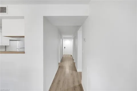 a view of a hallway with wooden floor and closet