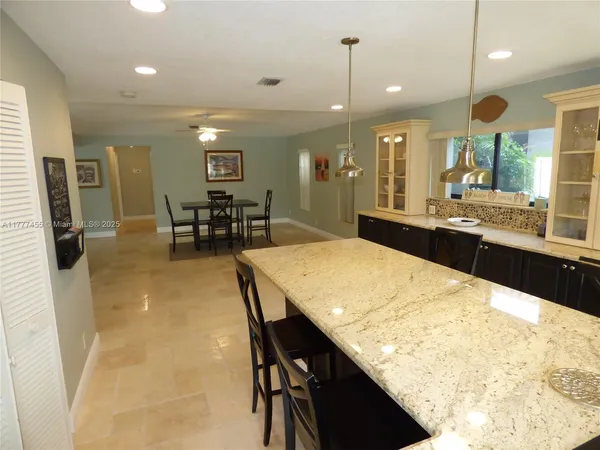 a kitchen with stainless steel appliances kitchen island granite countertop dining table chairs and a granite counter tops