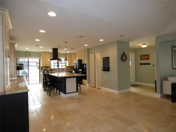 a open kitchen with kitchen island a refrigerator a dining table and chairs