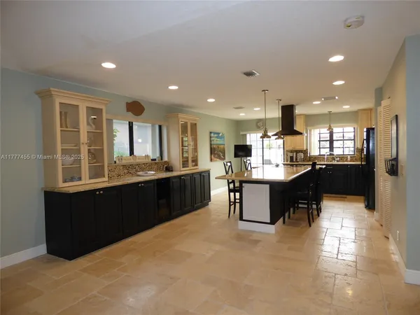 a large kitchen with kitchen island a sink a counter and a living room view
