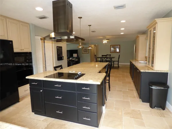 a kitchen with stainless steel appliances kitchen island granite countertop a stove a sink and a refrigerator
