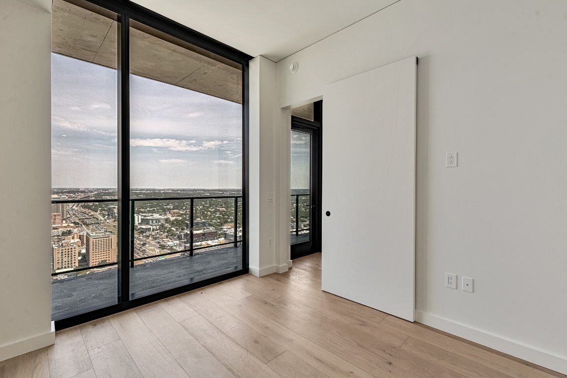 610 Davis Street, Unit 4406 Austin, TX 78701 - Photo 13 of 36 an empty room with wooden floor and windows with curtains