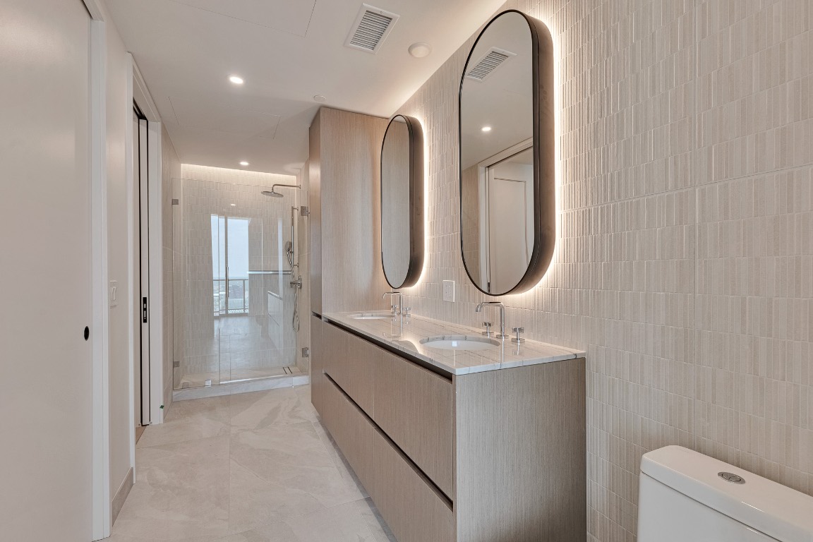 610 Davis Street, Unit 4406 Austin, TX 78701 - Photo 14 of 36 a bathroom with a granite countertop toilet a sink and a mirror