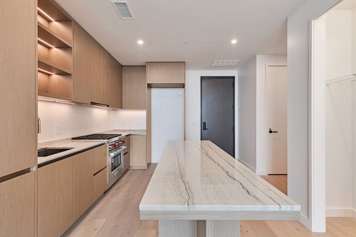 610 Davis Street, Unit 4406 Austin, TX 78701 - Photo 4 of 36 a kitchen with granite countertop white cabinets and stainless steel appliances