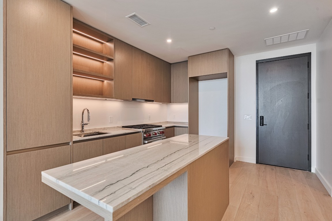 610 Davis Street, Unit 4406 Austin, TX 78701 - Photo 5 of 36 a kitchen with granite countertop stainless steel appliances and wooden cabinets