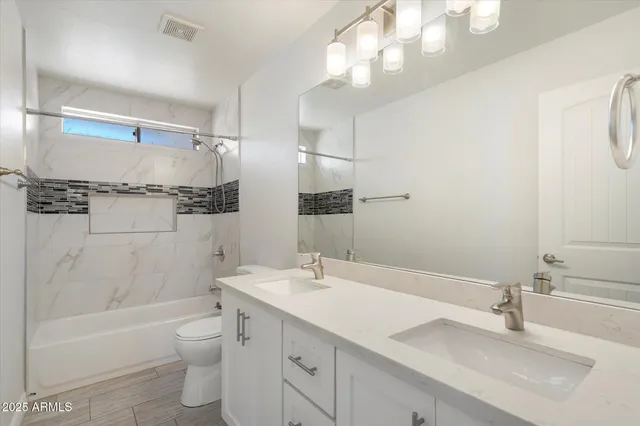 a bathroom with a granite countertop sink a toilet and shower