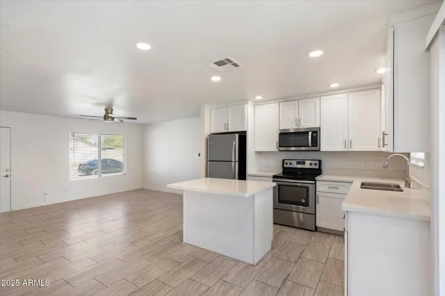 a kitchen with stainless steel appliances granite countertop a stove top oven a sink a refrigerator and white cabinets