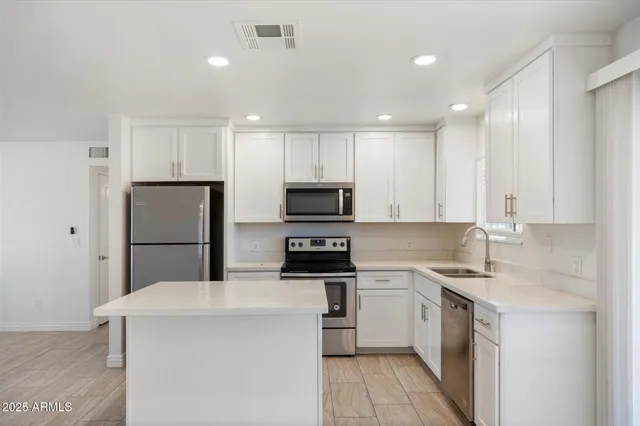 a kitchen with kitchen island a sink stainless steel appliances and cabinets