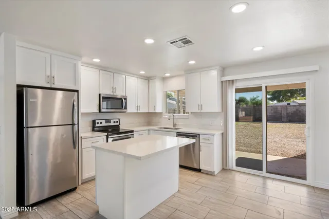 a kitchen with stainless steel appliances granite countertop a refrigerator a stove a sink a microwave and a refrigerator