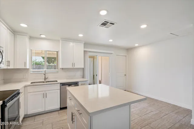 a kitchen with a sink dishwasher a stove and white cabinets with wooden floor