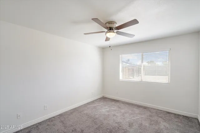 an empty room with a window and a ceiling fan