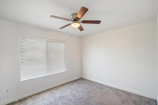 an empty room with a window and a fan