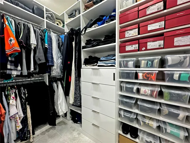 a view of walk in closet with clothes and shoes