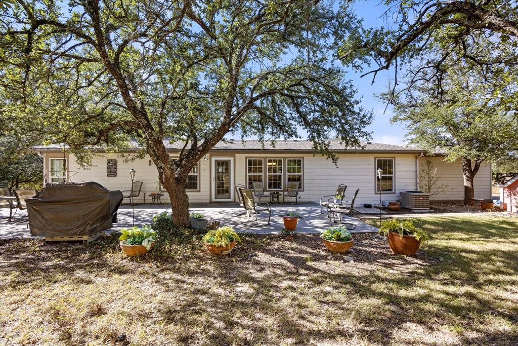 4474 South Fm 200 Nemo Nemo, TX 76070 - Photo 13 of 40 a view of a backyard with table and chairs potted plants and large tree