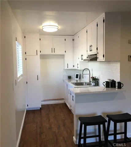 a kitchen with granite countertop a sink cabinets and refrigerator