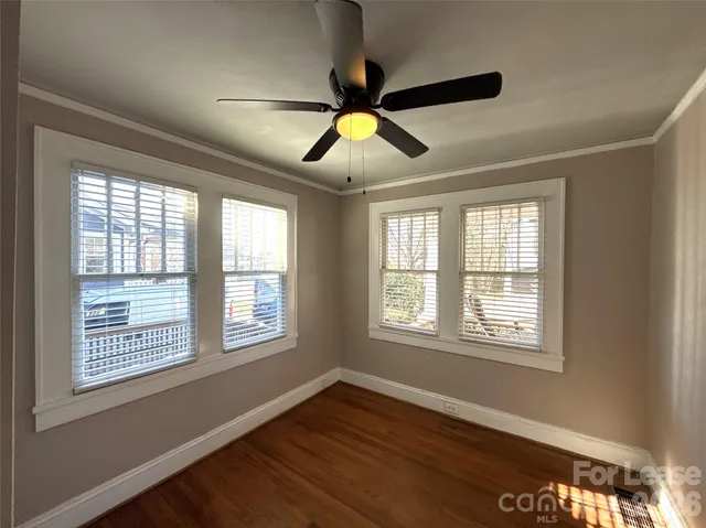 a view of an empty room with window and wooden floor