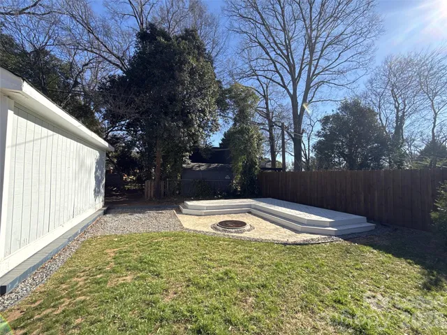 a view of backyard with large tree and wooden fence
