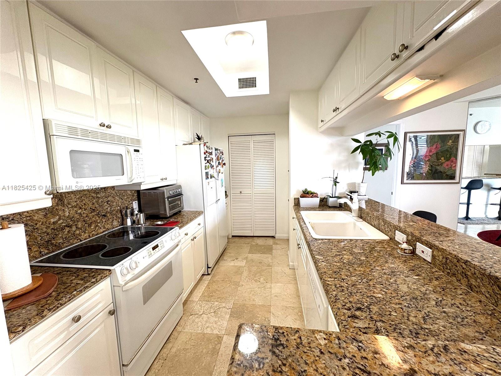 808 Brickell Key Drive, Unit 1103 Miami, FL 33131 - Photo 6 of 12 a large white kitchen with a stove and a sink