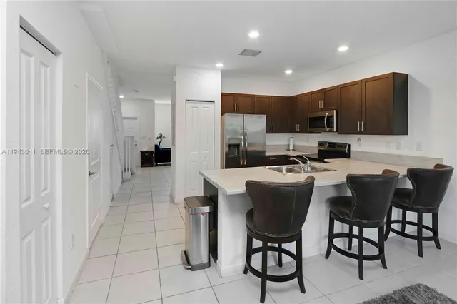 a kitchen with stainless steel appliances kitchen island granite countertop a refrigerator and a stove top oven