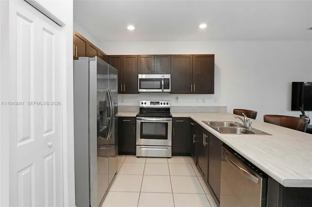 a kitchen with stainless steel appliances a stove a sink a microwave and a refrigerator