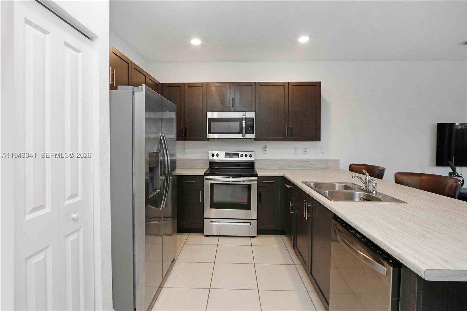 10125 Southwest 228th Terrace Miami, FL 33190 - Photo 13 of 26 a kitchen with stainless steel appliances a stove a sink a microwave and a refrigerator