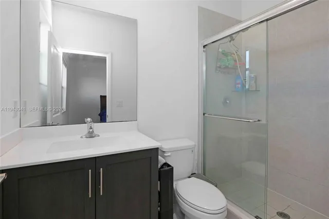 a bathroom with a sink a toilet a mirror and shower