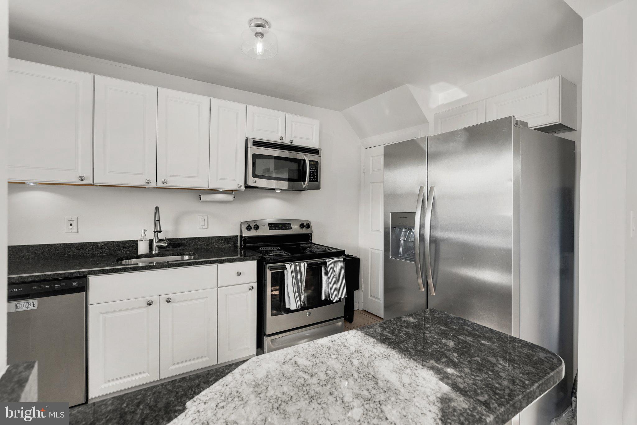 40 Bladen Road Baltimore, MD 21221 - Photo 12 of 44 a kitchen with granite countertop a refrigerator sink and white cabinets