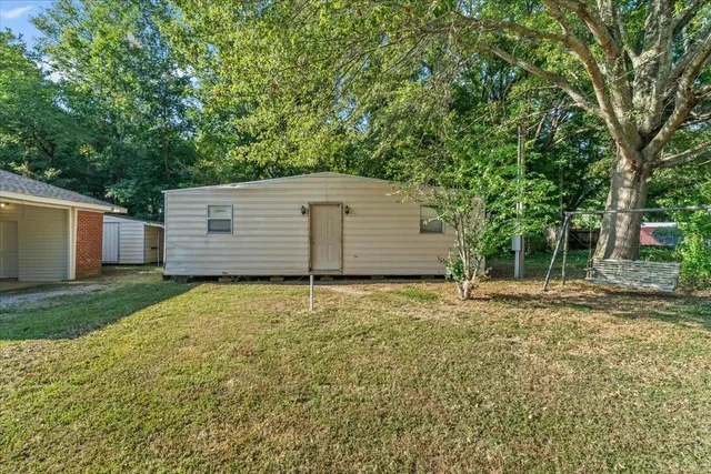 a backyard of a house with plants and large tree