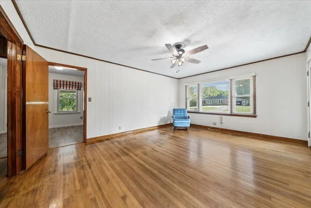 a view of an empty room with a window and wooden floor