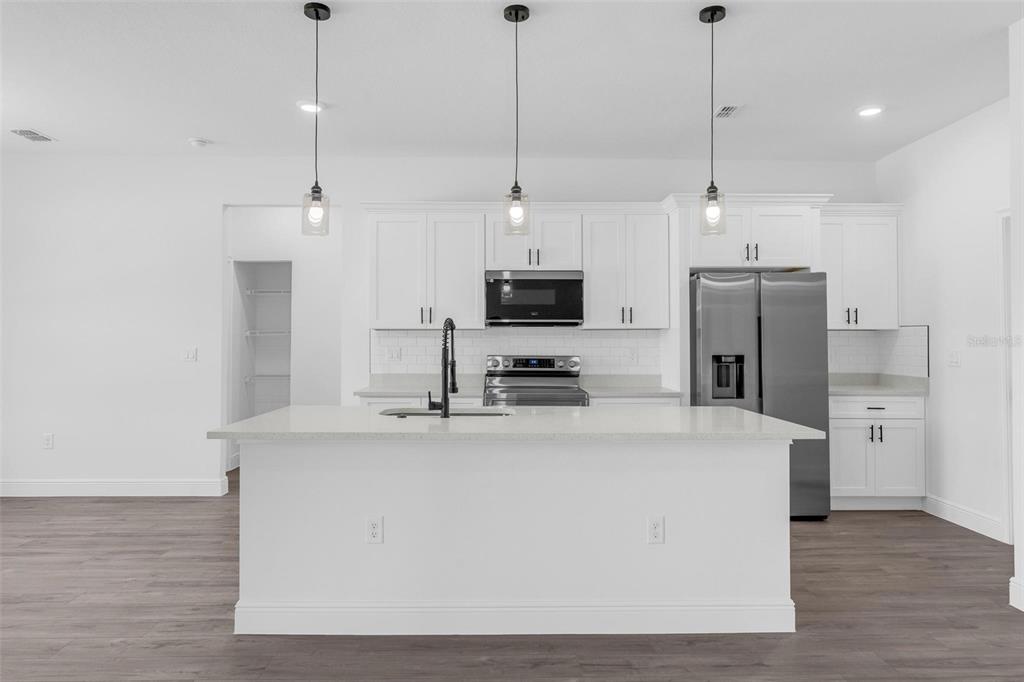 17109 Southwest 41st Circle Ocala, FL 34473 - Photo 13 of 72 a kitchen with stainless steel appliances kitchen island a refrigerator a stove a sink and a center island