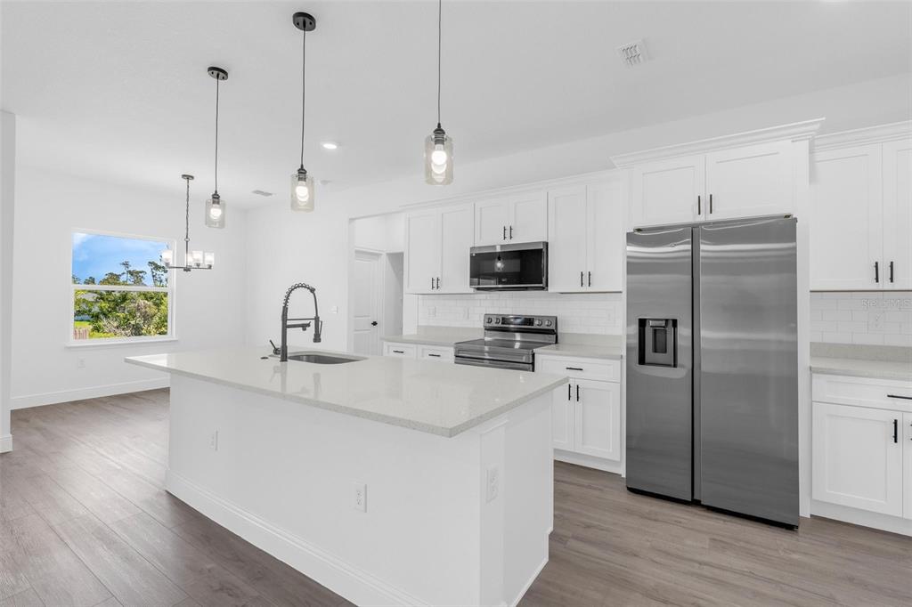 17109 Southwest 41st Circle Ocala, FL 34473 - Photo 15 of 72 a kitchen with stainless steel appliances a sink a refrigerator a stove a microwave and island