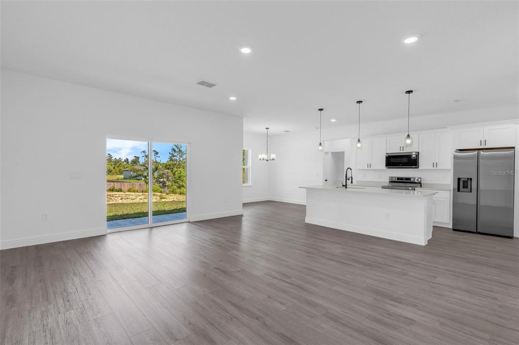 17109 Southwest 41st Circle Ocala, FL 34473 - Photo 20 of 72 a view of kitchen with stainless steel appliances granite countertop a stove top oven a refrigerator with white cabinets and wooden floor