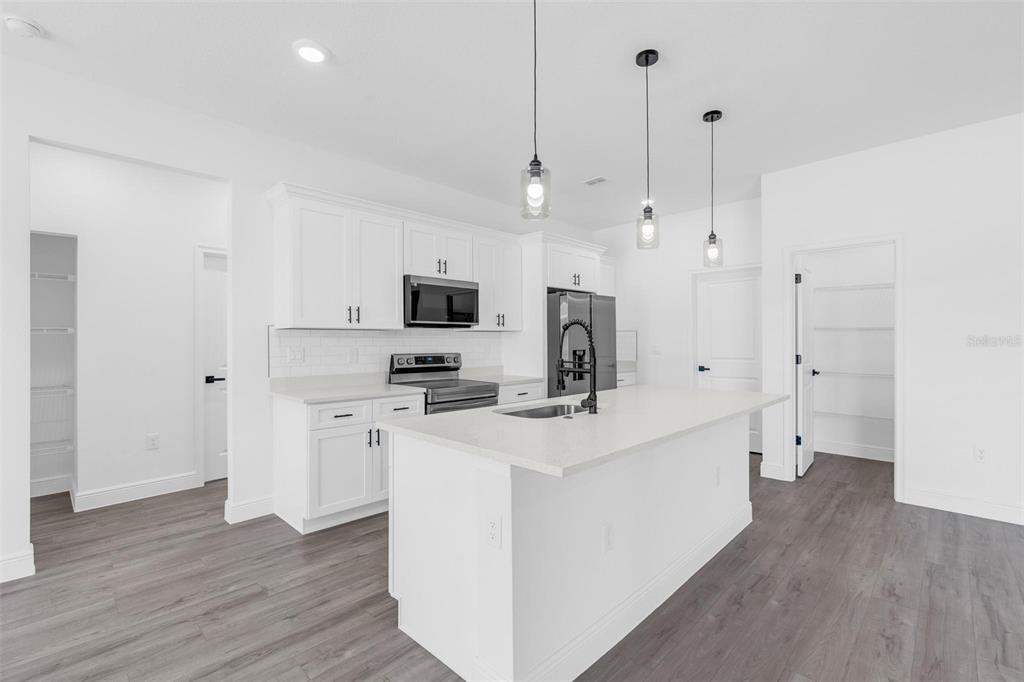 17109 Southwest 41st Circle Ocala, FL 34473 - Photo 22 of 72 a kitchen with stainless steel appliances a stove top oven a sink a refrigerator a center island and cabinets