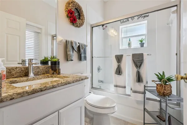a bathroom with a granite countertop sink a toilet and a mirror