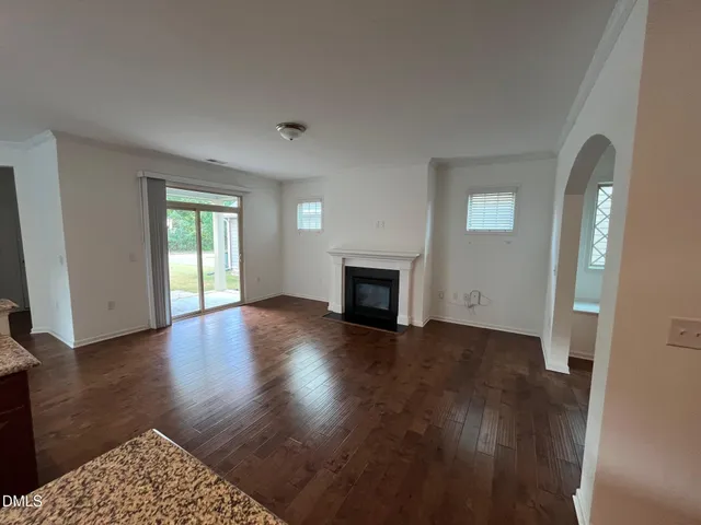 an empty room with wooden floor a fireplace and windows