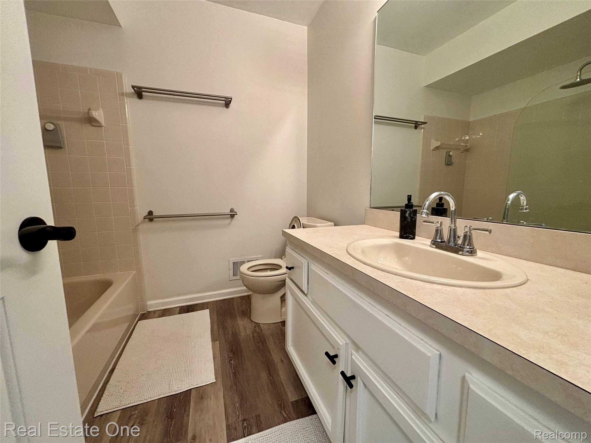 66 Meadow Wood Drive Rochester, MI 48307 - Photo 17 of 20 Bathroom featuring a white vanity with an integrated sink, a large wall-mounted mirror, and wood-finish flooring