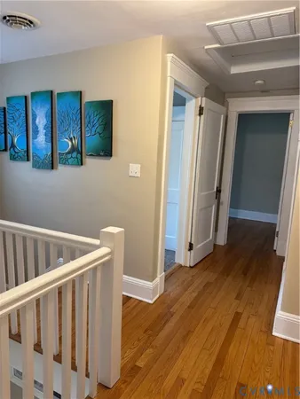 a view of a hallway with wooden floor and stairs