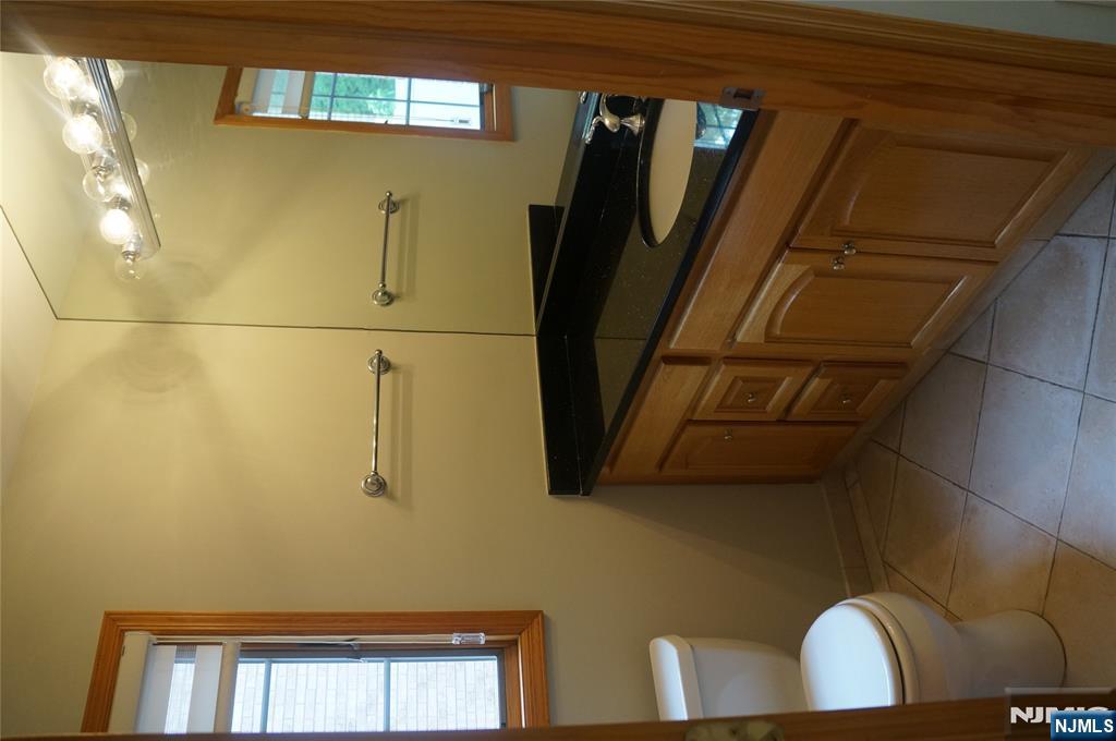 520 7th Street, Unit B Palisades Park, NJ 07650 - Photo 7 of 22 a bathroom with a granite countertop sink a toilet and a mirror