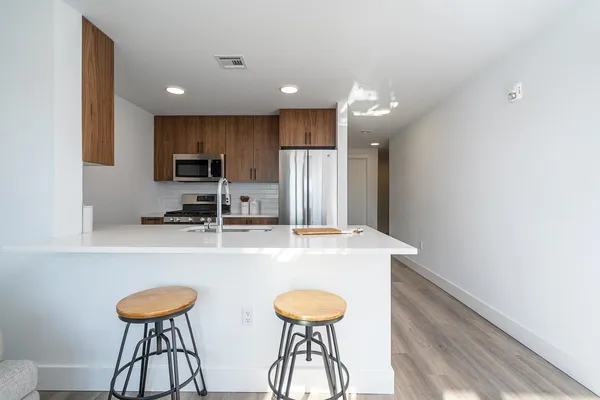 a kitchen with stainless steel appliances a dining table chairs refrigerator and microwave