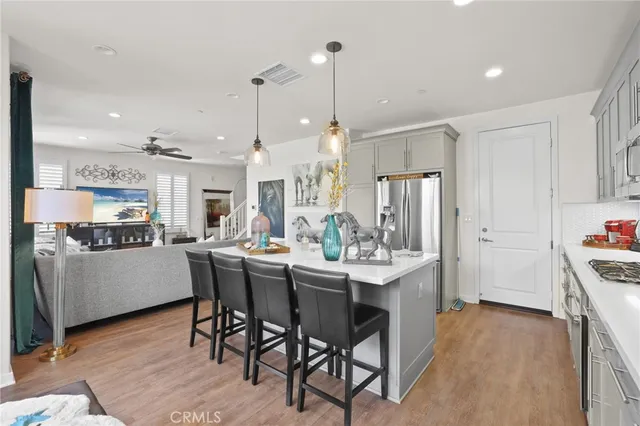 a kitchen with stainless steel appliances kitchen island granite countertop a table chairs and a refrigerator