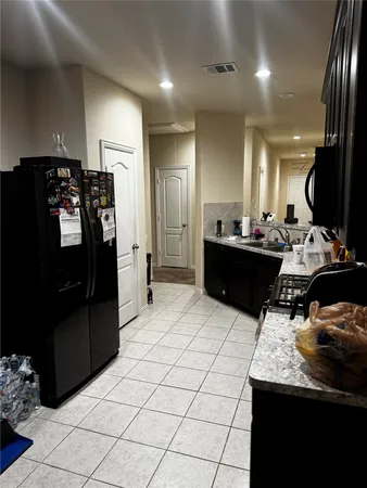 a kitchen with granite countertop a refrigerator and a stove top oven