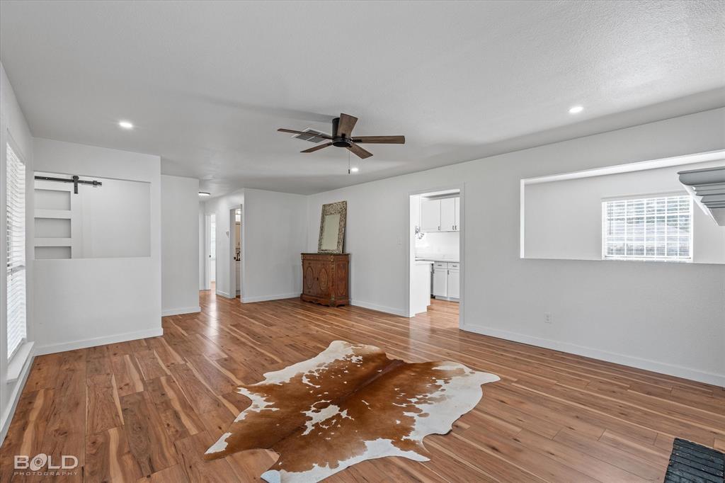 3407 Hickory Ridge Road Shreveport, LA 71108 - Photo 12 of 35 Unfurnished living room with a barn door, plenty of natural light, ceiling fan, hardwood / wood-style floors, and recessed lighting