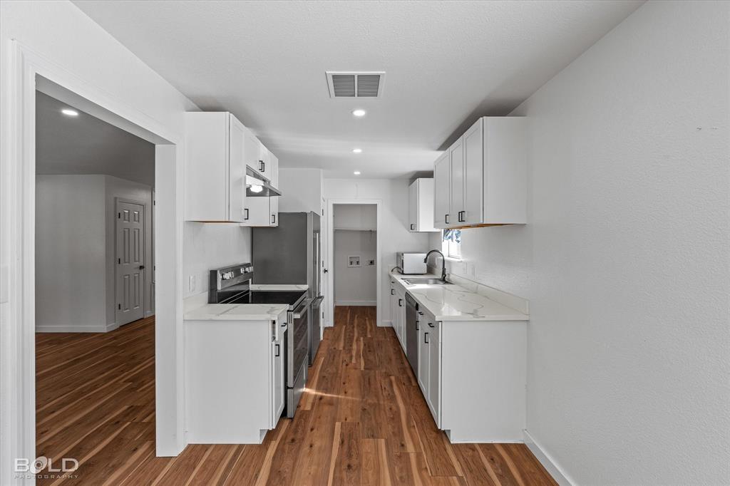 3407 Hickory Ridge Road Shreveport, LA 71108 - Photo 15 of 35 Kitchen with appliances with stainless steel finishes, white cabinets, dark wood-type flooring, light stone countertops, and recessed lighting