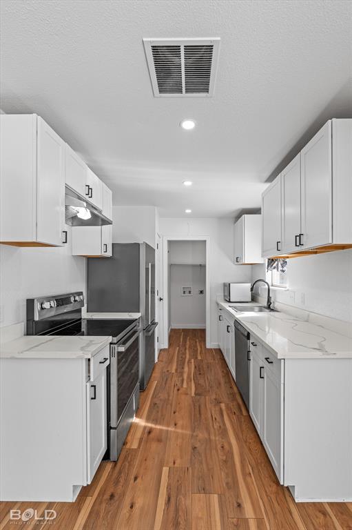 3407 Hickory Ridge Road Shreveport, LA 71108 - Photo 18 of 35 Kitchen featuring white cabinets, stainless steel appliances, light wood-style floors, light stone countertops, and recessed lighting